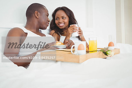 Ethnic couple having breakfast in their bed