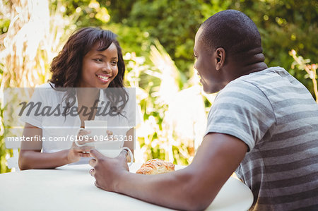 Pretty woman holding mug with boyfriend in the garden