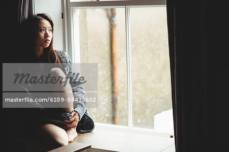 Brunette sitting on the edge of the window at home