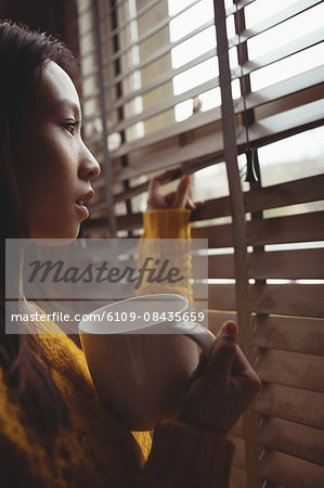 Brunette drinking coffee and looking at the window