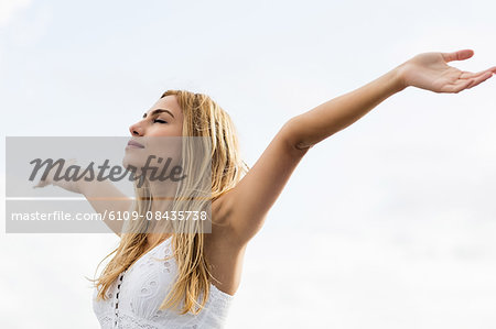 Beautiful blonde woman with arms outstretched in the coastline