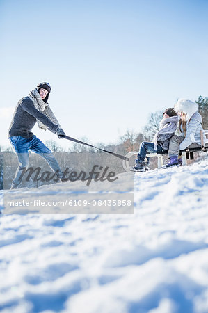 Father and children playing with sled on a beautiful snowy day