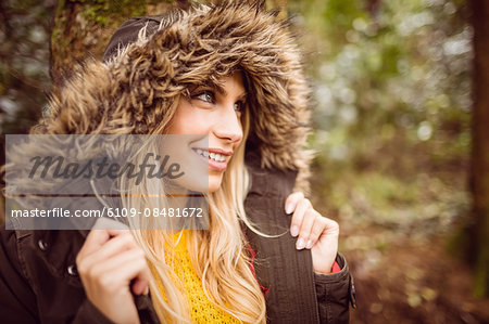 Beautiful blonde woman wearing hooded jumper in the woods