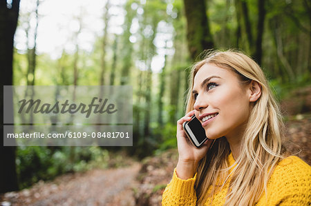 Beautiful blonde woman phone calling in the woods