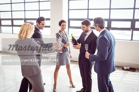 Business people popping bottle of champagne at the office