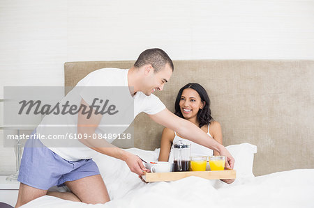 Young couple having breakfast in bed at home in bedroom