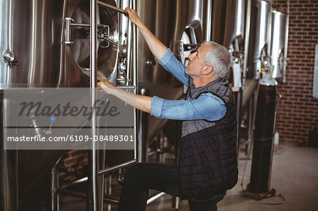 Happy brewer checking large vats at the local brewery