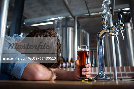 Drunk man sleeping at the bar holding his pint