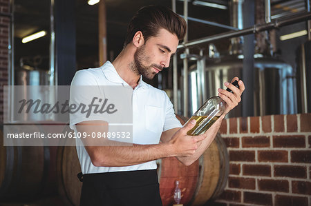 Winemaker examining bottle of white wine in a brewery