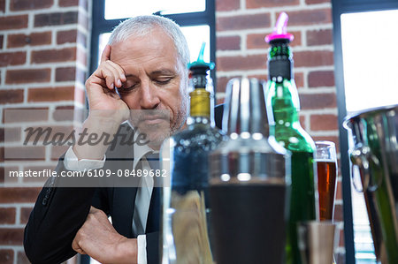 Tired businessman leaning on counter in a pub