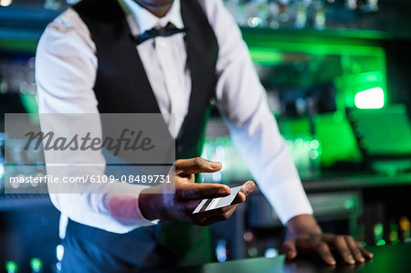 Bartender accepting a credit card at bar counter in bar