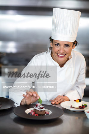 Chef putting finishing touch on dessert in a commercial kitchen Chef putting finishing touch on dessert in a commercial kitchen