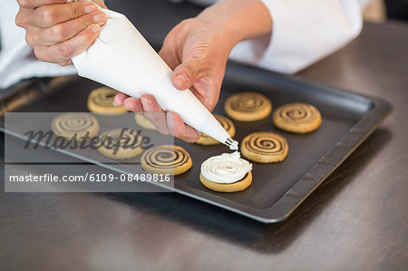 Chef piping icing on biscuits in a commercial kitchen