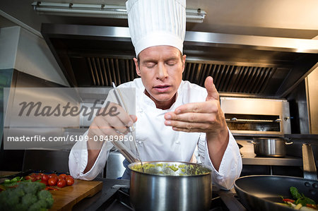 Happy chef smelling his dish in a commercial kitchen