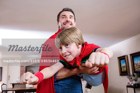 Father and son pretending to be superhero in living room