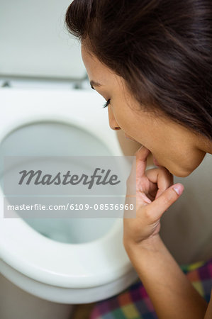 Young woman about to vomit into a commode toilet