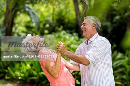 Senior woman laughing while dancing with man