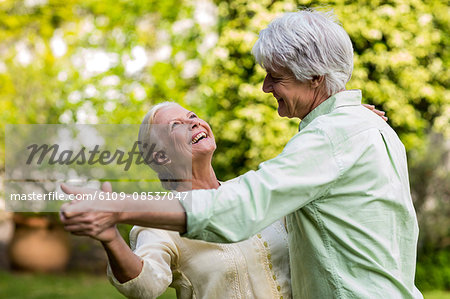 Smiling senior woman looking up while dancing with man Smiling senior woman looking up while dancing with man