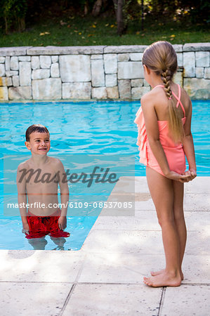 Siblings standing at swimming pool Siblings standing at swimming pool
