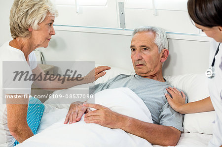 Caregiver and woman comforting senior man