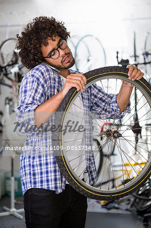 Worker using phone while repairing bikes