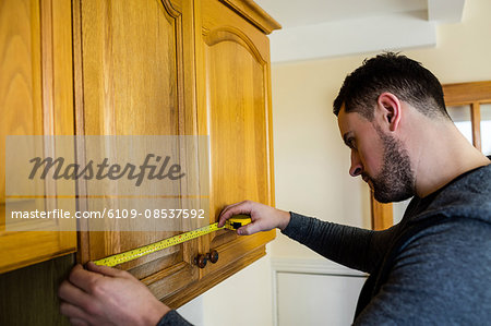 Handyman measuring a furniture with measuring tape