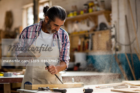 Carpenter carving wood with chisel