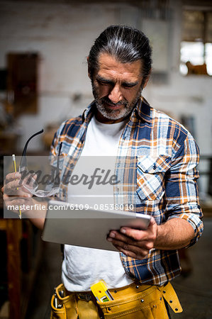 Carpenter using digital tablet in workshop