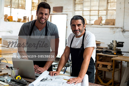 Portrait of two carpenters standing together in workshop