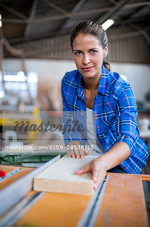 Portrait of female carpenter with wooden plank