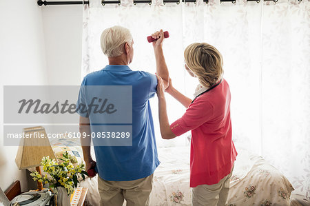 Senior man doing fitness with the help of a nurse