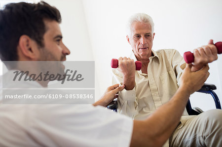 Nurse helping senior man with doing exercises Nurse helping senior man with doing exercises
