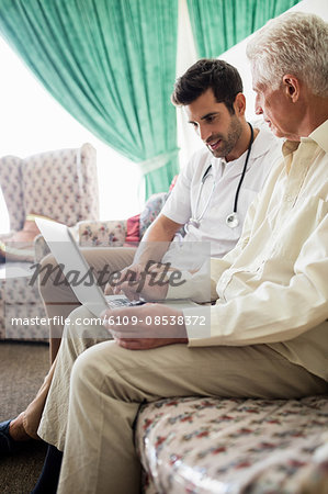 Nurse and senior man using laptop