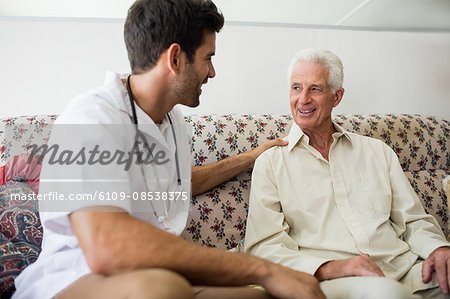 Nurse and senior man sitting on sofa