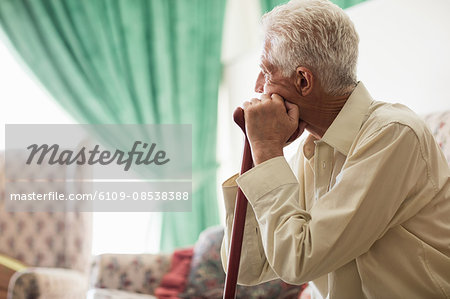Thoughtful senior man sitting with a cane