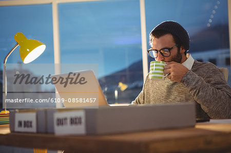 Hipster using a computer and drinking coffee