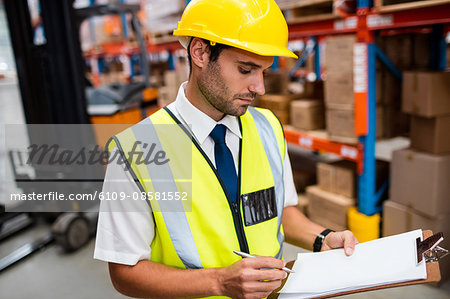Warehouse manager checking list on his clipboard