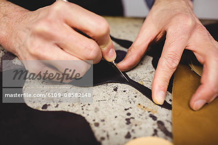 Close up of hands cutting leather