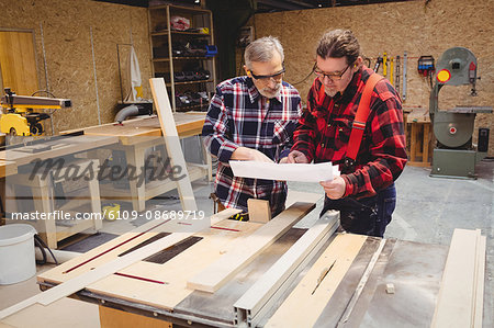 Duo of carpenters studying plans in workshop