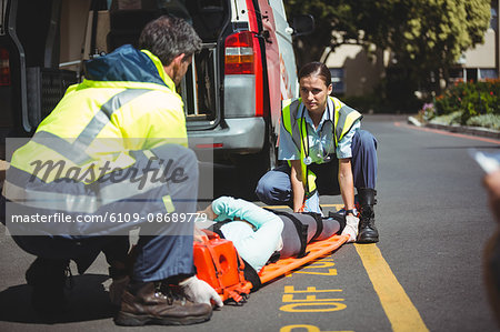 Ambulance crew about to carry a jogger in their vehicle during the day