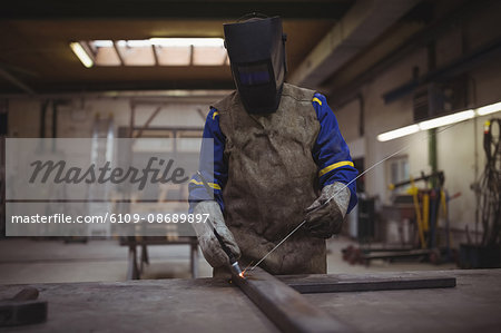 Welder using a welding torch in his workshop