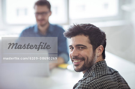 Portrait of smiling editor with coworker at creative office