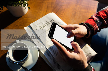 High angle view of customer texting on cellphone at cafe