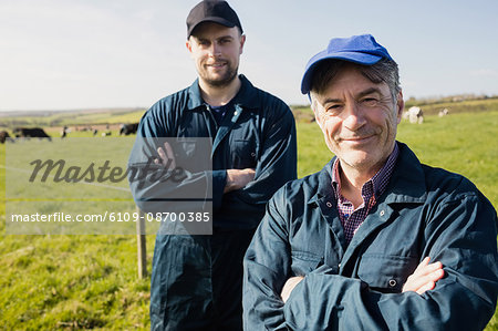 Portrait of confident farm workers standing on grassy field