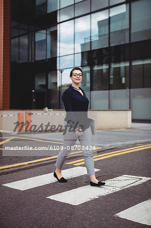 Full length portrait of confident businesswoman walking on road
