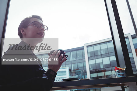 Young businesswoman holding coffee cup in cafe