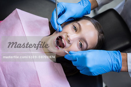 Dentist examining a young patient with tools at dental clinic