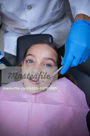 Dentist examining a young patient with tools at dental clinic