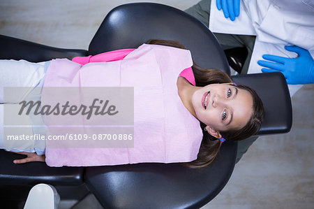 Smiling young patient sitting on dentist's chair at clinic