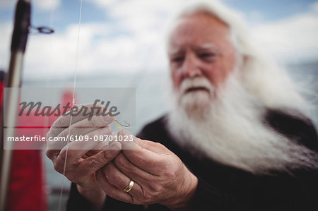 Close-up of fisherman adjusting fishing hook on fishing boat